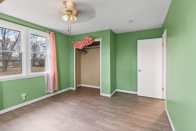 unfurnished bedroom with ceiling fan, a textured ceiling, light wood-type flooring, and a closet