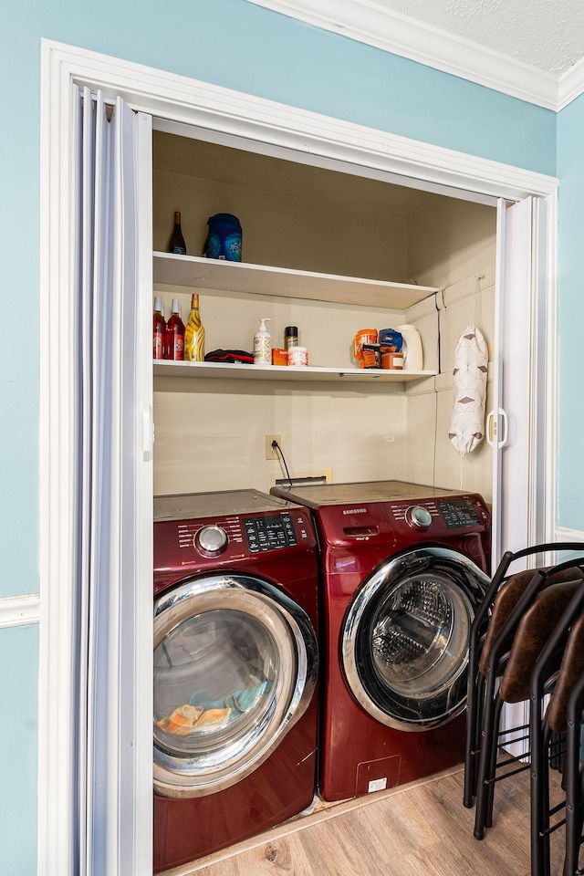 clothes washing area with hardwood / wood-style flooring, ornamental molding, separate washer and dryer, and a textured ceiling