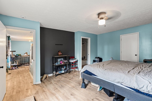 bedroom featuring ceiling fan, light hardwood / wood-style flooring, and a textured ceiling