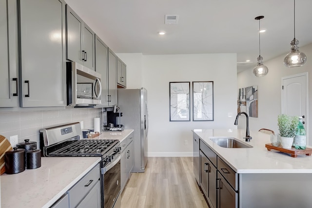 kitchen with light stone counters, sink, decorative light fixtures, and appliances with stainless steel finishes