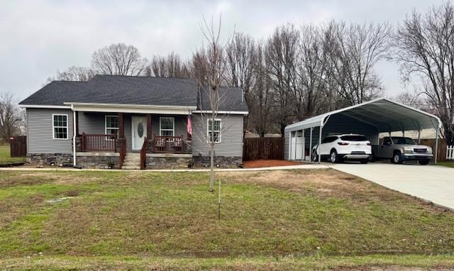 ranch-style house featuring a front yard, a carport, and covered porch