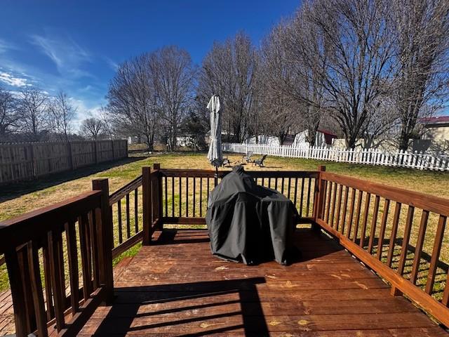 wooden deck featuring grilling area and a lawn