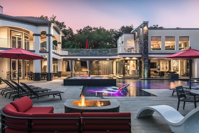 back house at dusk featuring an outdoor living space with a fire pit