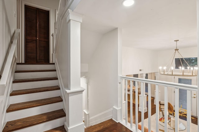 staircase with hardwood / wood-style floors and an inviting chandelier