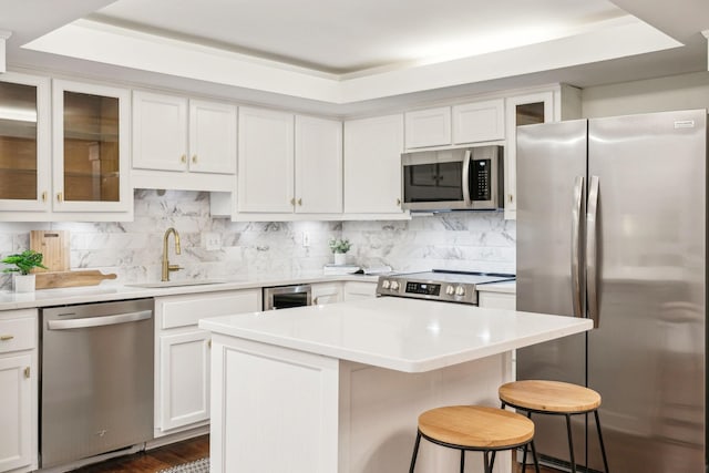 kitchen featuring sink, a center island, backsplash, appliances with stainless steel finishes, and white cabinets