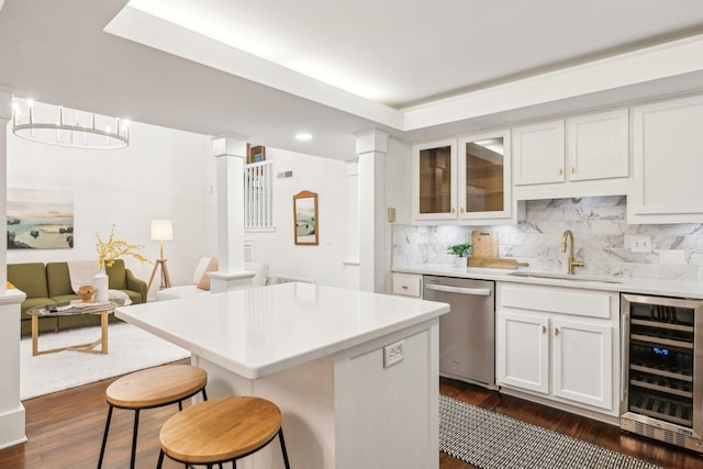 kitchen featuring sink, white cabinets, decorative backsplash, stainless steel dishwasher, and beverage cooler