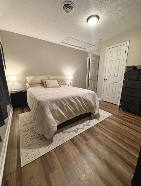 bedroom featuring a textured ceiling and dark hardwood / wood-style flooring