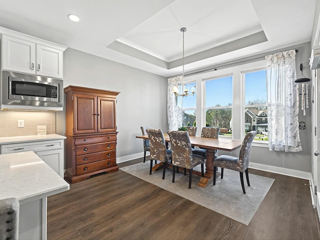 dining room with crown molding, a notable chandelier, dark hardwood / wood-style flooring, and a tray ceiling