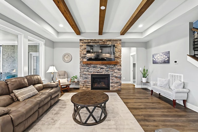 living room with a stone fireplace, hardwood / wood-style floors, and beam ceiling