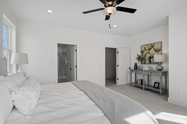 bedroom featuring ceiling fan, light colored carpet, and ensuite bath