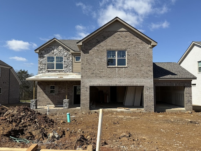 view of front of home with a garage, a patio, stone siding, roof with shingles, and brick siding