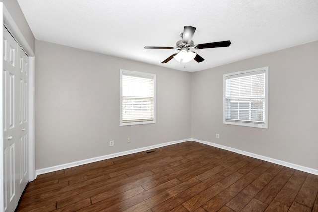 unfurnished bedroom featuring dark wood-type flooring, a closet, and ceiling fan