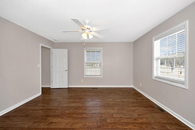 unfurnished room with plenty of natural light, dark wood-type flooring, and ceiling fan