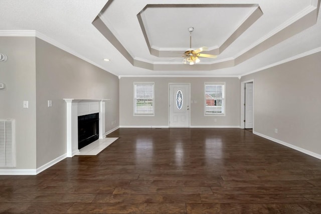 unfurnished living room featuring crown molding, a tray ceiling, dark hardwood / wood-style flooring, ceiling fan, and a premium fireplace