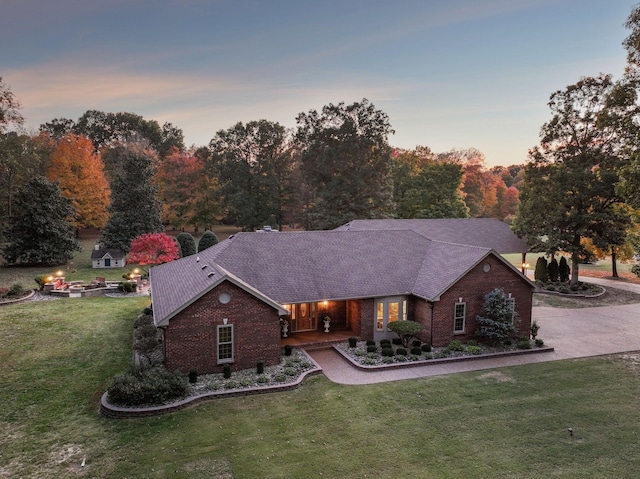 ranch-style house featuring a fire pit and a lawn