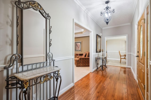 hallway with an inviting chandelier, wood-type flooring, and ornamental molding