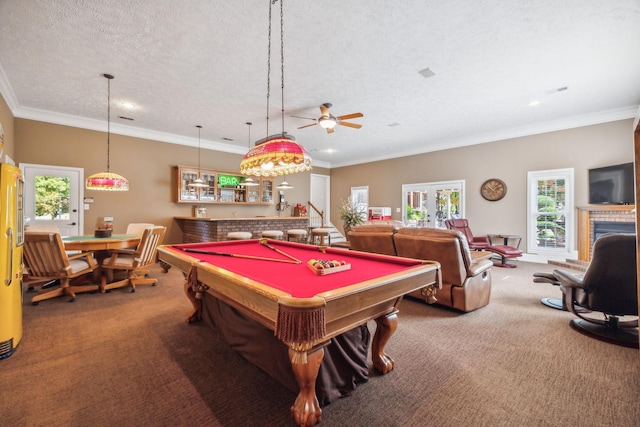 rec room with a tiled fireplace, crown molding, a textured ceiling, and carpet flooring