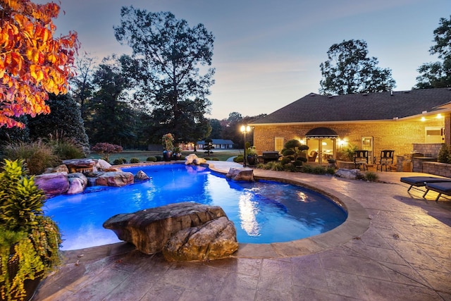 pool at dusk featuring a patio