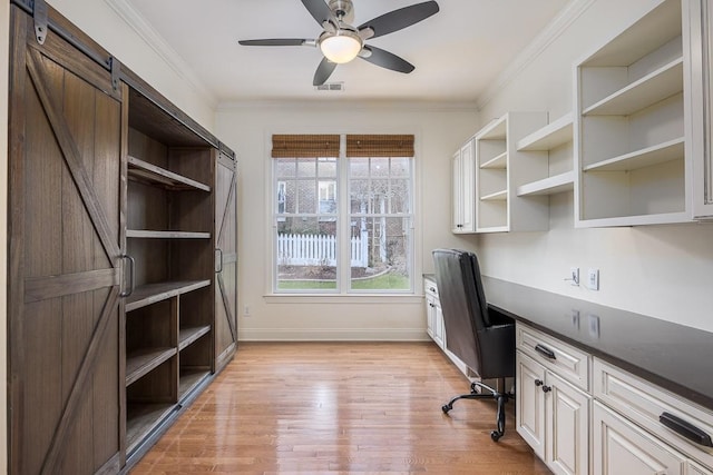 unfurnished office with light hardwood / wood-style flooring, built in desk, ornamental molding, and ceiling fan