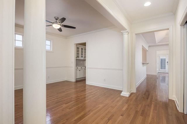 empty room featuring ornate columns, ornamental molding, dark hardwood / wood-style floors, and ceiling fan