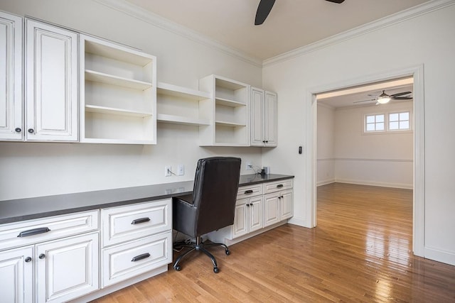 office space featuring ceiling fan, ornamental molding, built in desk, and light hardwood / wood-style flooring