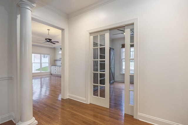 corridor featuring crown molding, decorative columns, and hardwood / wood-style floors