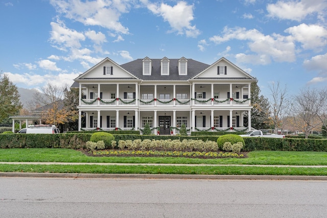 neoclassical / greek revival house featuring a front yard, a balcony, and covered porch