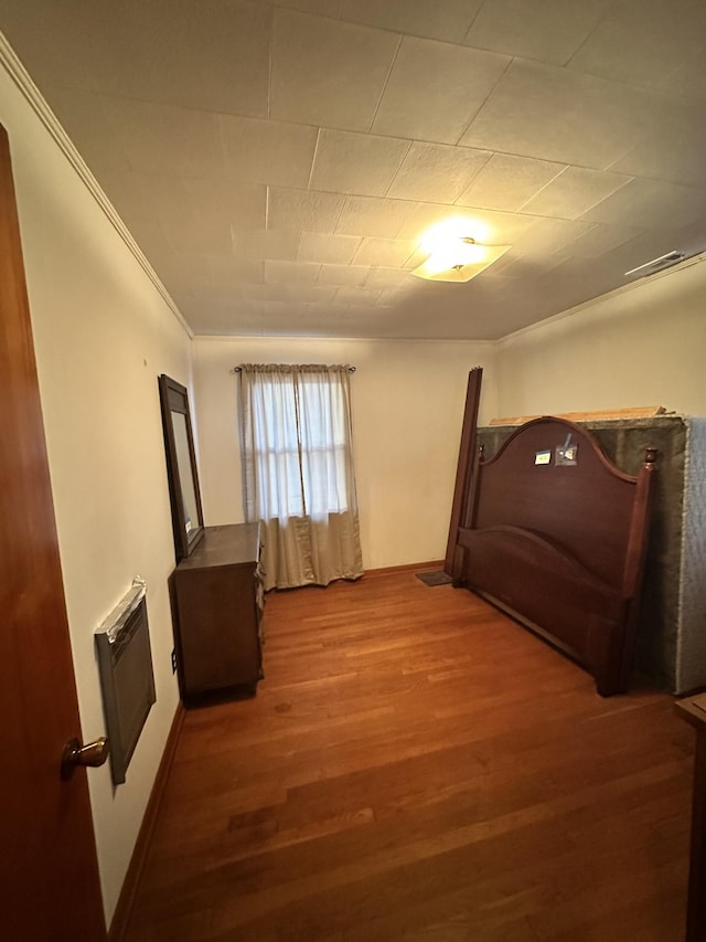 bedroom with hardwood / wood-style flooring, ornamental molding, and heating unit