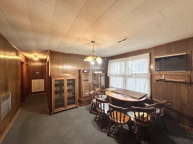 dining space featuring wooden walls, dark carpet, and a notable chandelier