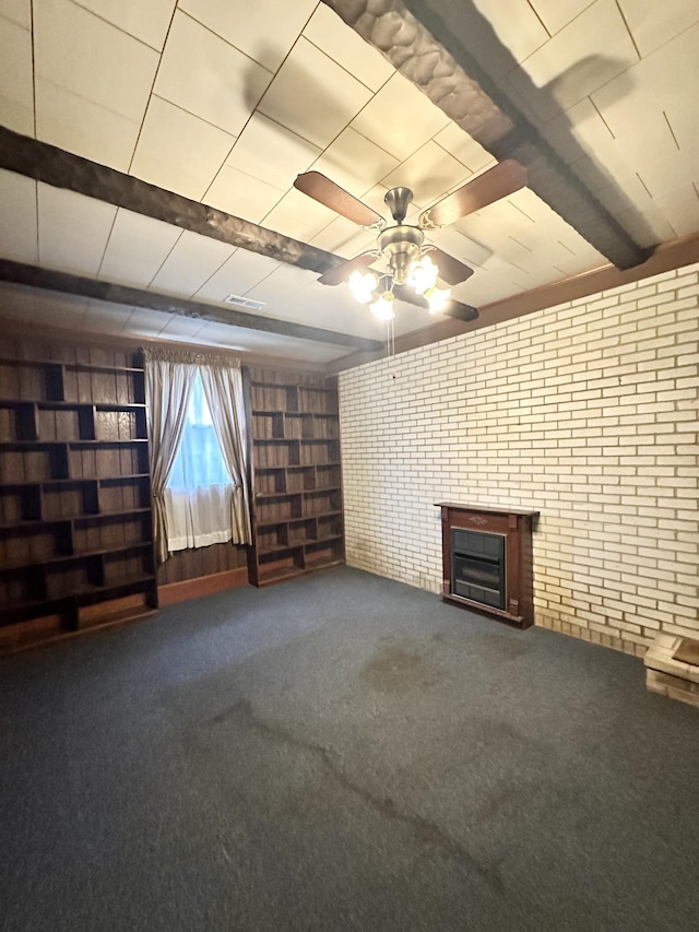 unfurnished living room featuring ceiling fan, carpet, beamed ceiling, and brick wall