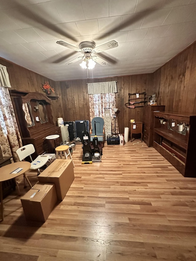 interior space with ceiling fan, wooden walls, and light hardwood / wood-style flooring