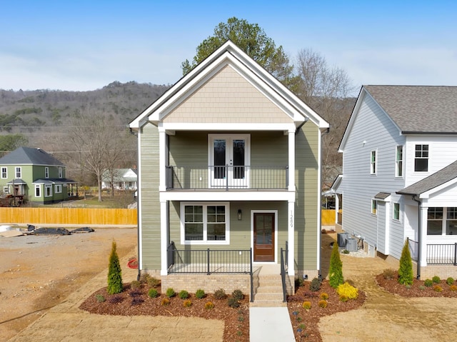 front of property featuring a porch, a balcony, cooling unit, and french doors