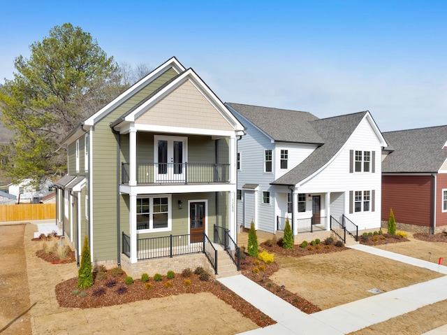 view of front of home featuring french doors, a balcony, and covered porch