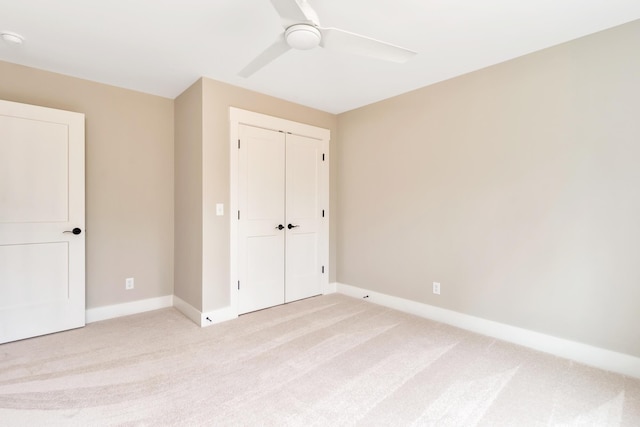 unfurnished bedroom with light carpet, ceiling fan, and a closet