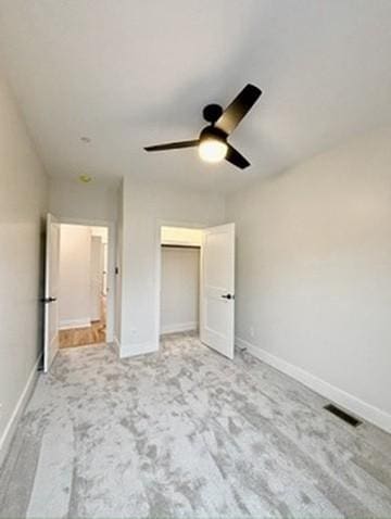 unfurnished bedroom with ceiling fan, light carpet, and a closet