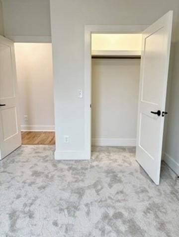 unfurnished bedroom featuring light colored carpet and a closet