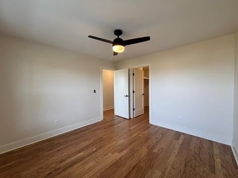 unfurnished bedroom with dark wood-type flooring, ceiling fan, and a spacious closet