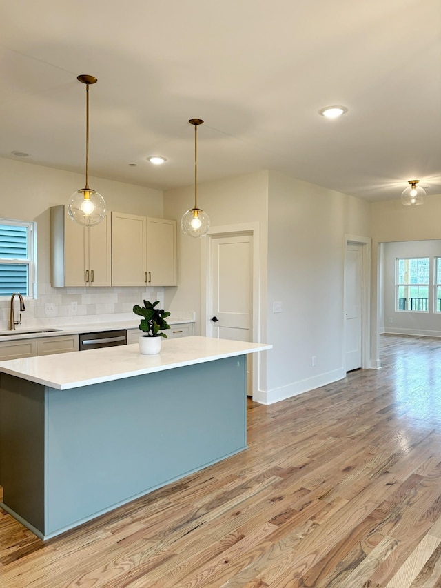 kitchen with a kitchen island, light hardwood / wood-style floors, sink, and hanging light fixtures