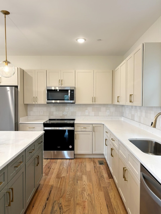 kitchen featuring hanging light fixtures, white cabinetry, appliances with stainless steel finishes, and sink