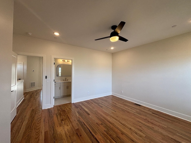 unfurnished bedroom featuring ensuite bath, dark wood-type flooring, and ceiling fan