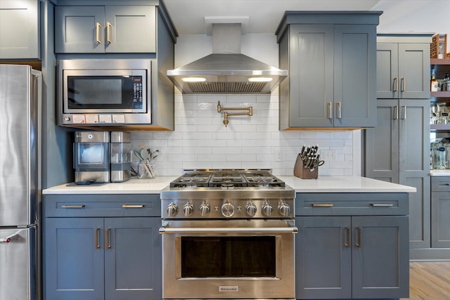 kitchen with stainless steel appliances, range hood, light hardwood / wood-style flooring, and backsplash