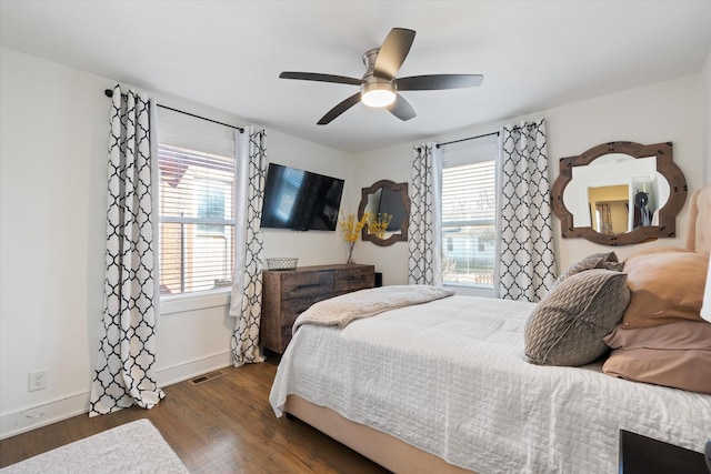 bedroom featuring multiple windows, dark hardwood / wood-style floors, and ceiling fan