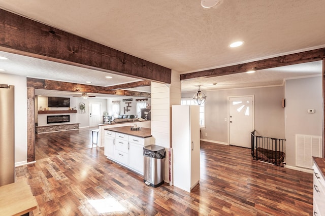 kitchen with pendant lighting, beam ceiling, dark wood-type flooring, and white cabinets