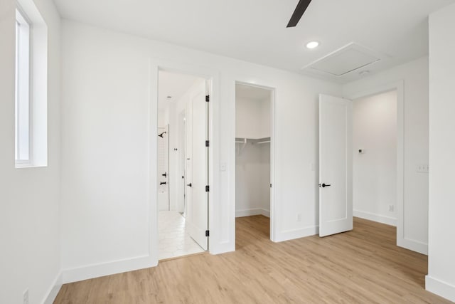 unfurnished bedroom featuring connected bathroom, a spacious closet, light wood-type flooring, a closet, and ceiling fan