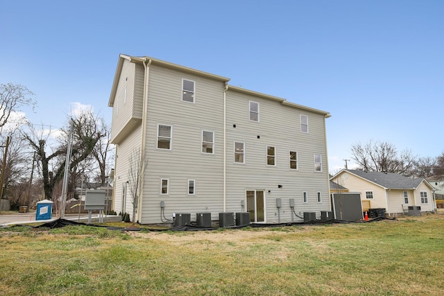 rear view of property featuring a lawn and central air condition unit