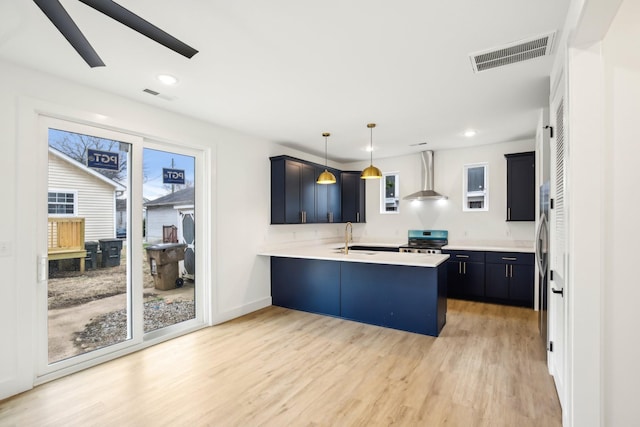 kitchen with sink, stainless steel range with electric cooktop, hanging light fixtures, kitchen peninsula, and wall chimney exhaust hood