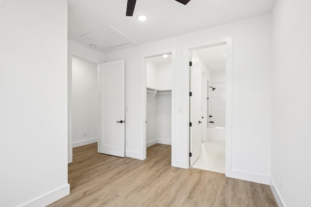 unfurnished bedroom with ensuite bathroom, a spacious closet, light hardwood / wood-style flooring, a closet, and ceiling fan