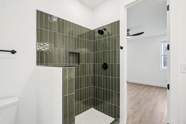 bathroom with ceiling fan, wood-type flooring, toilet, and a tile shower