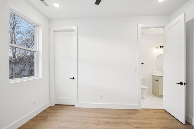 unfurnished bedroom with connected bathroom and light hardwood / wood-style floors