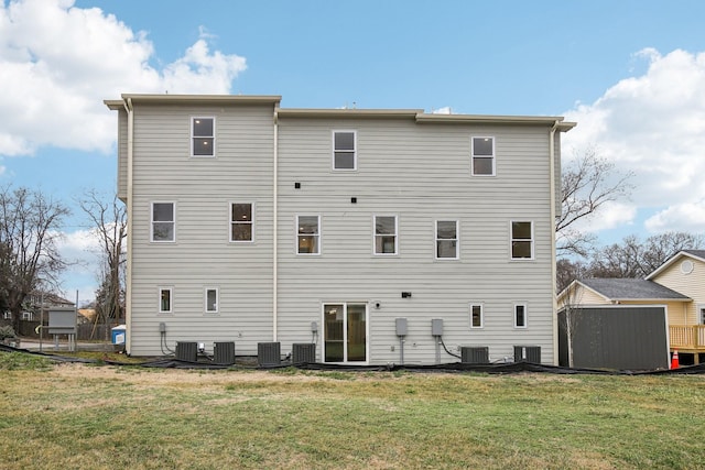 rear view of property featuring cooling unit and a lawn